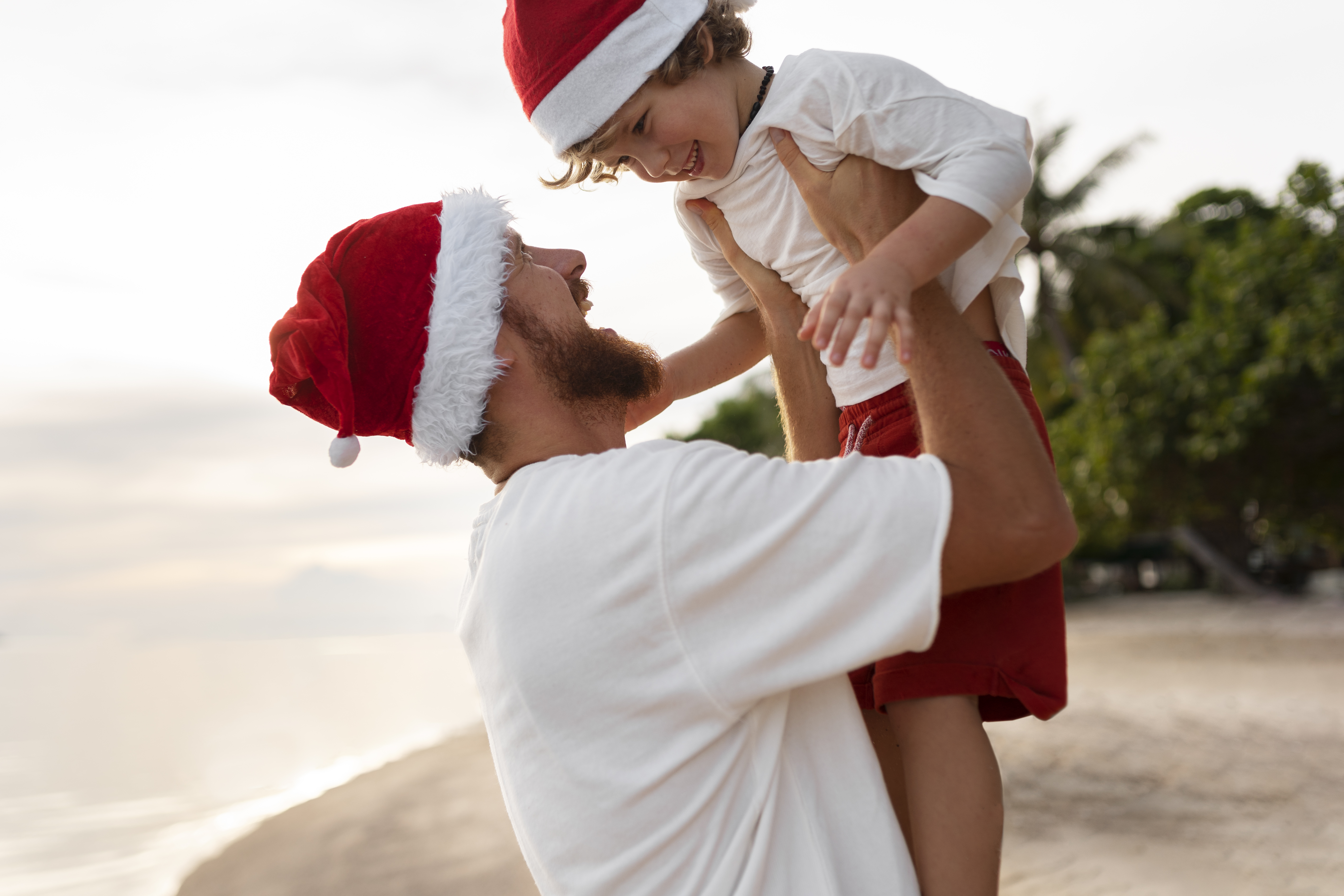 father-and-son-on-the-beach-with-santa-hats